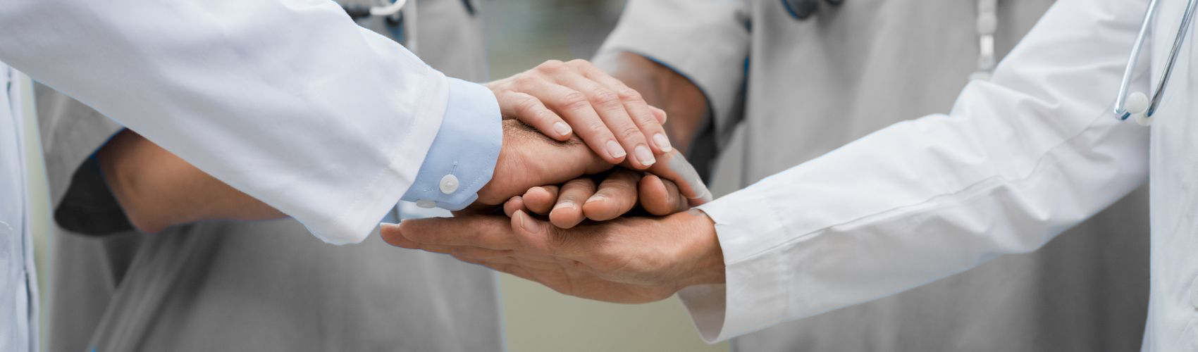 Close-up of medical professionals stacking hands in a gesture of teamwork and solidarity.